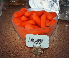 a bowl filled with carrots sitting on top of a counter next to a sign that says snowmen noses little baby carrots