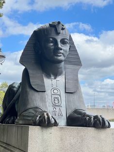 a statue of an egyptian pharaoh is shown in front of a blue sky with clouds