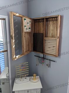 an open wooden cabinet with jewelry hanging from it's sides in a small bathroom