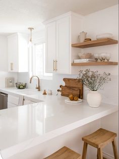 a kitchen with white counter tops and wooden stools