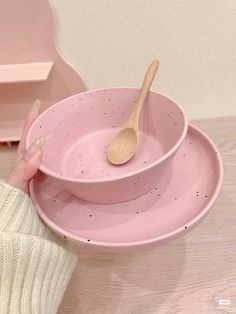 a person holding a wooden spoon over two pink bowls