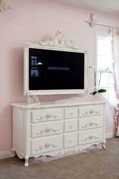 a large white dresser with a flat screen tv on it's side in a pink room