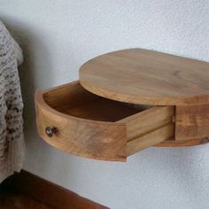 a wooden shelf with two open drawers on the wall next to a crocheted blanket