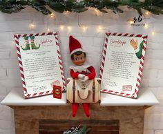 an elf sitting on top of a fire place next to two christmas cards and a bag