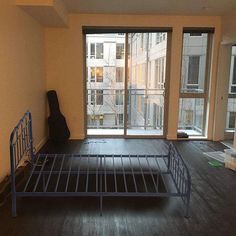 an empty room with a metal bed frame in front of a sliding glass door that leads to the balcony