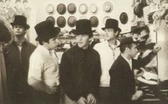 black and white photograph of men in top hats looking at something on the wall behind them