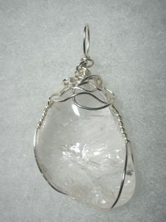 Clear Quartz Pendant Wire Wrapped in .925 Sterling Silver Round Wire This inspiring stone exhibits transparent clarity with multiple internal reflection and refraction with some iridescent display. As it is clear, reflecting and refracting any background color, it is very versatile and can be worn with any color of clothing; a non-standard shape, non-uniform surface, and internal crystal plane/fine fracture reflection and refraction make this stone of more appeal to an artistic view than a puris Silver Gemstone Crystals For Jewelry Making, Clear Quartz Gemstone Crystals, Handmade Silver Crystals For Jewelry Making, Handmade Silver Crystal Pendant, Elegant Silver Crystals For Gift, Elegant Silver Crystals As A Gift, Elegant Silver Crystals For Gifts, Silver Quartz Crystals For Gifts, Silver Healing Mineral Crystals