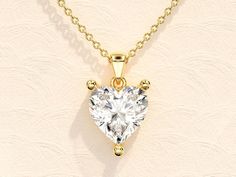 a heart - shaped diamond pendant hangs on a gold chain against a white wall background