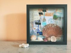 a sea shell and seashells in a shadow box on a marble countertop