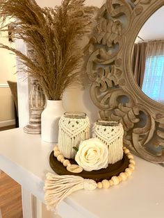 a white table topped with two vases filled with flowers and tasseled candles