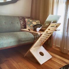 a laptop computer sitting on top of a wooden stand next to a couch in a living room