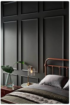 a bedroom with black walls and a metal bed frame in the middle, along with a green plant next to it