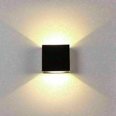 a square light that is on the side of a wall with white walls behind it