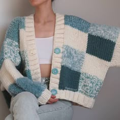 a woman sitting on the floor wearing a blue and white checkered cardigan sweater