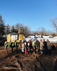 a group of people standing next to each other in front of a bulldozer