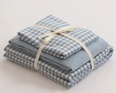 stack of blue and white checkered cloths with ribbon tied around the edges, stacked on top of each other