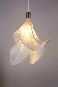 a white light hanging from a ceiling with two leaves attached to the lightshade