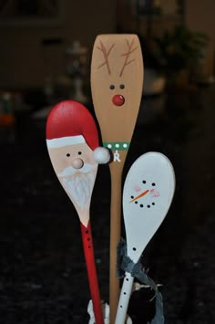 three wooden spoons with santa claus and snowman on them