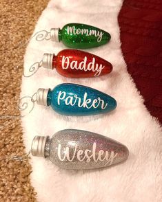 four personalized christmas ornament ornaments on a white furnishing with red, green, and blue glitter