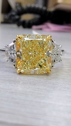 a fancy yellow diamond ring sitting on top of a table