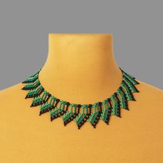 a woman wearing a green and black beaded necklace on top of a mannequin