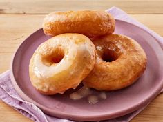 three glazed donuts on a purple plate