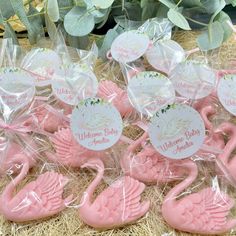 pink flamingos are wrapped in clear cellophane and placed on straw with welcome baby tags