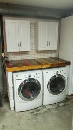 a washer and dryer in a small room with white cabinets on the wall