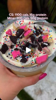 a person holding up a cup filled with ice cream and oreo cookie toppings