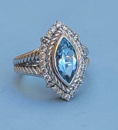 Judith Ripka Blue Topaz and CZ Sterling Silver Ring - Size 11 Marquise cut blue topaz bezel set with a twisted rope border, with 20 round CZs surrounding the blue topaz. Thick double cable band which tapers to a solid band in the back. The underside has Judith Ripka's signature fleur-de-lis cut-out. In great vintage condition. Fit: Sits on the ring mandrel at exactly size 11, and fits as a size 11. 11.58 grams Marked: Judith Ripka, 925, Thailand, CZ  Photos taken outside in natural light. Kindly disregard any weird reflections on the silver, (such as green tinting from the trees).  In very good vintage condition, but might have wear consistent with a well-loved piece. ba5634 Ring Mandrel, Rope Border, Silver Cocktail, Judith Ripka, Marquise Cut, Cocktail Ring, Cocktail Rings, Bezel Setting, 11 11