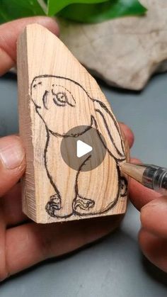 someone is drawing a dog on a piece of wood