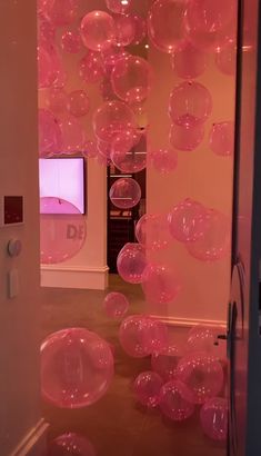 pink balloons floating in the air near a television