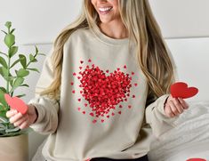 a woman sitting on a bed holding two red hearts