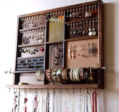 a wooden shelf filled with lots of different types of jewelry hanging from it's sides