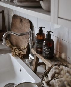 two bottles of hand soap sitting on a wooden shelf next to a sink