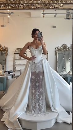 a woman taking a selfie in front of a mirror wearing a white wedding dress