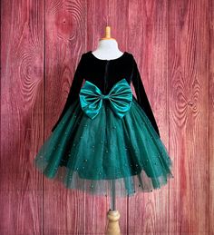 Little Darln Boutique  Our enchanting Knee Length flower girl dresses are sure to turn heads! This beautiful elegant sophisticated dress is handmade, the bodice consists of soft black velvet material, the back of the dress consists of a hunter green satin detachable bow, with zipper for closure. The skirt consists of 4 Hunter Green layers of tulle with the top layer consisting with sowed in pearl beads. The fifth layer is made of lining with crinoline for fullness.  Dress Is Pictured with a petticoat NOT INCLUDED https://www.etsy.com/listing/1316417982/white-knee-length-petticoat-wedding?click_key=41cb8b0ae4587efa582b0a433f3f5e0cde12aec0%3A1316417982&click_sum=af1df37b&ref=shop_home_active_1 Visit our store, more items to come!  https://www.etsy.com/shop/LittledarlnBoutique?ref=profile_hea Hunter Green Flower Girl Dress, Elegant Tulle Holiday Dress For Festive Occasions, Green Christmas Princess Dress For Dress-up, Fitted Tutu Dress For Christmas Fancy Dress, Fitted Christmas Tutu Dress For Fancy Dress, Holiday Princess Dress With Bow, Elegant Festive Tulle Princess Dress, Elegant Green Pageant Dress For Dress-up, Fitted Tulle Princess Dress For Christmas