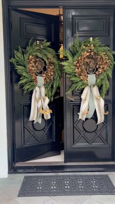 two wreaths on the front doors of a house