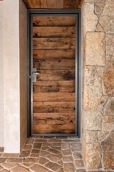 a wooden door is open on a stone building with brick flooring and white walls