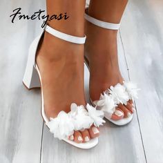 a woman's feet wearing white high heels with ruffles on the toes