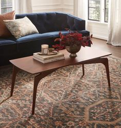 a living room with a blue couch, coffee table and rug in front of it