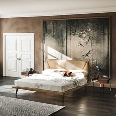 a bedroom with a large painting on the wall above the bed and wooden flooring