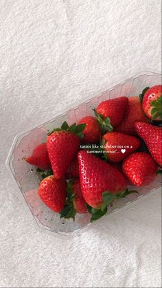 a plastic container filled with strawberries on top of a white tablecloth covered floor