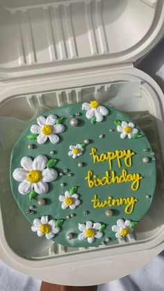 a birthday cake in a plastic container with flowers on it