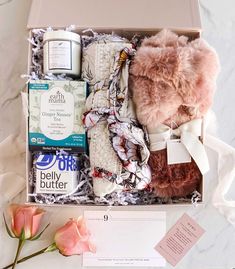 an open box with some items in it next to a pink rose on a table