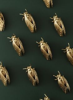 many gold bug like objects are arranged on a green surface, including one in the middle