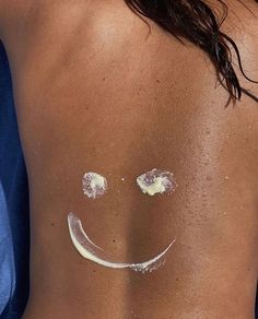 the back of a woman's body with white powder on it and a smiley face drawn on her stomach