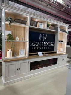 an entertainment center with white cabinets and wooden shelves in a showroom or office area