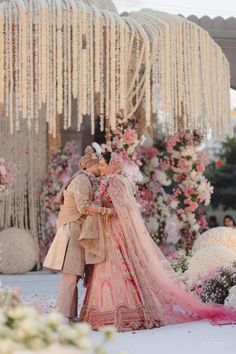 a bride and groom standing in front of a flower covered gazebo