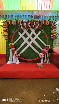 a man and woman standing in front of a red carpeted stage with flowers on it